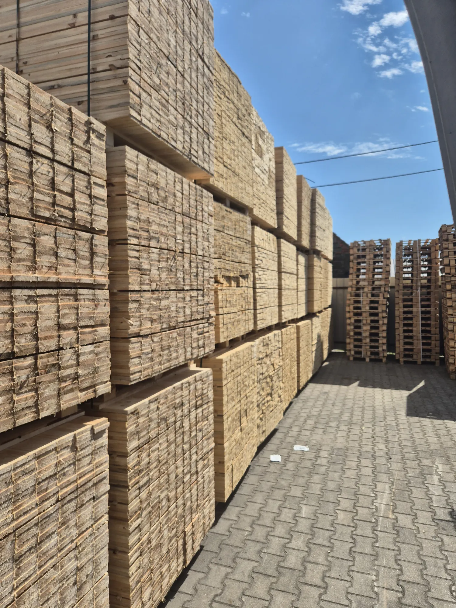 Stosy desek paletowych na placu produkcyjnym PSP